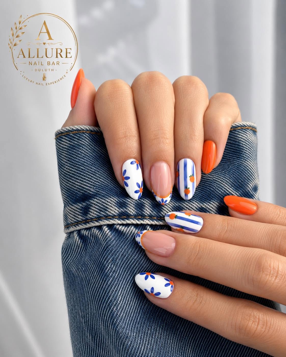 Orange nails with white floral and stripe accent nails at Allure Nail Bar Duluth