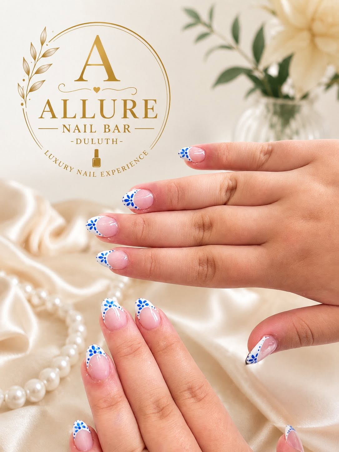 White nails with blue floral nail art and pearl accents at Allure Nail Bar Duluth