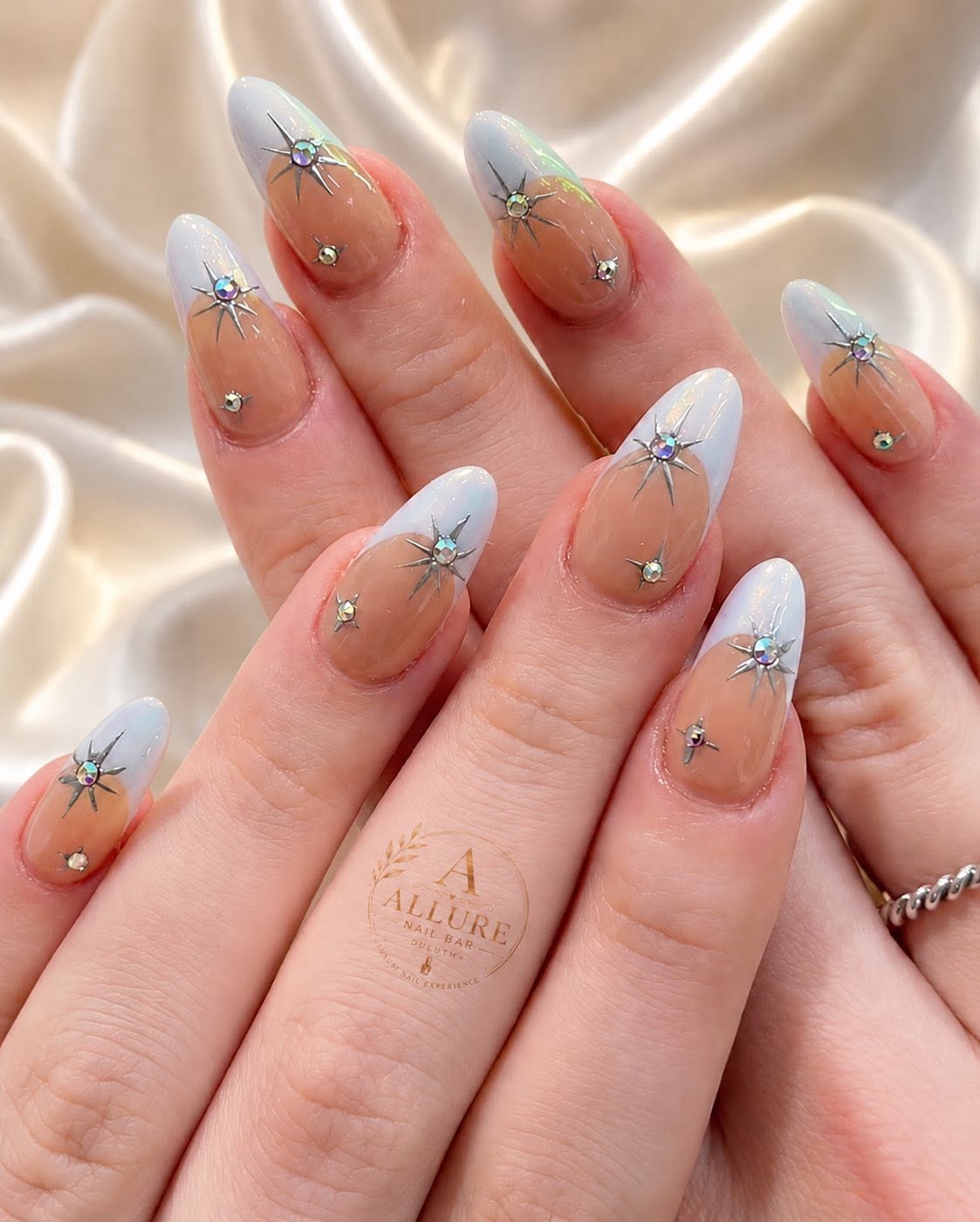 Iridescent white French tips with celestial star charms at Allure Nail Bar Duluth